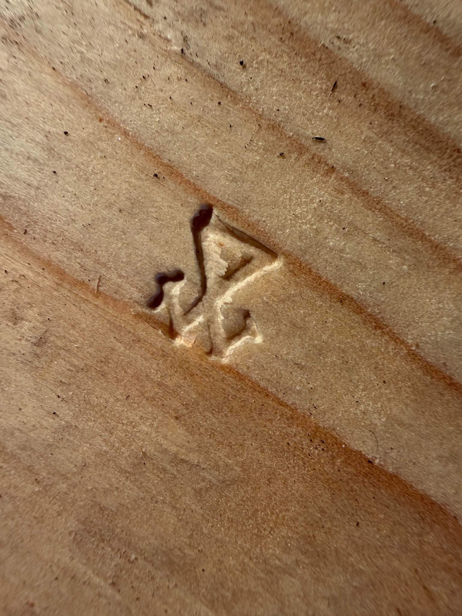 A triangular maker’s mark stamped into wood
