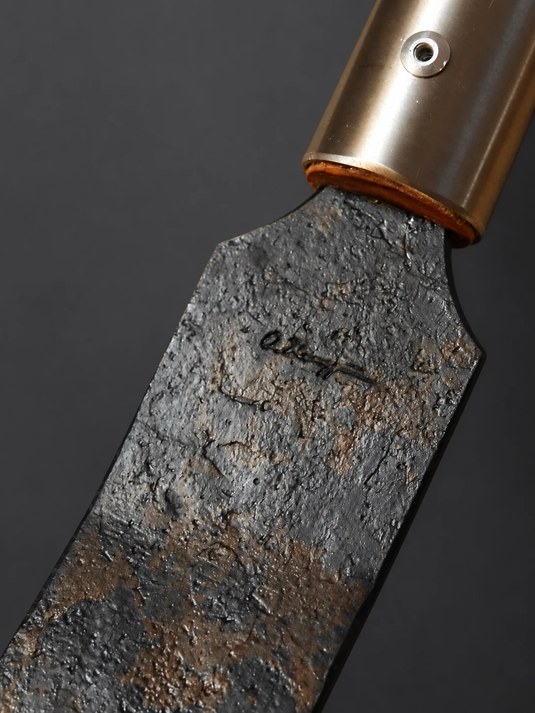 Maker’s mark on a forged blade, with the background retouched to neutral gray